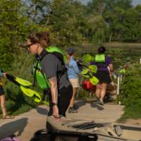 people picking up kayaks to load into the water